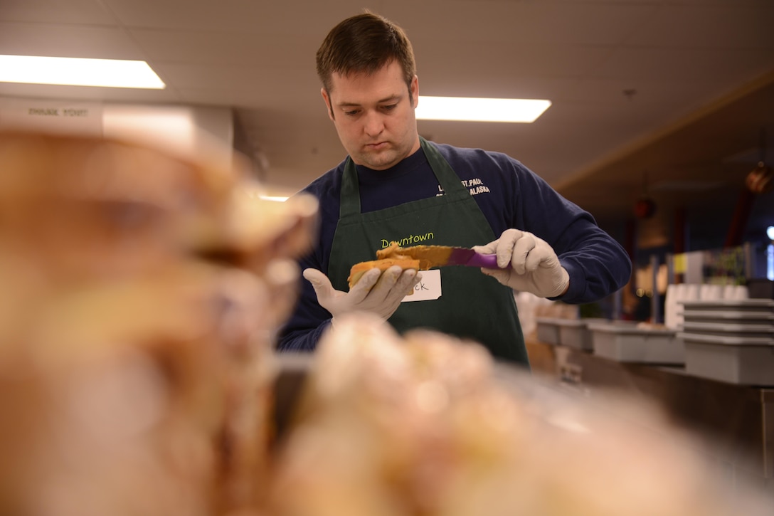 Coast Guard Lt. j.g. Richard Sprouse makes sandwiches while volunteering at the Downtown Soup Kitchen Hope Center in Anchorage, Alaska, Nov. 29, 2016. Sprouse and other Sector Anchorage members helped make food and care packages for the homeless. Coast Guard photo by Petty Officer 1st Class Bill Colclough.