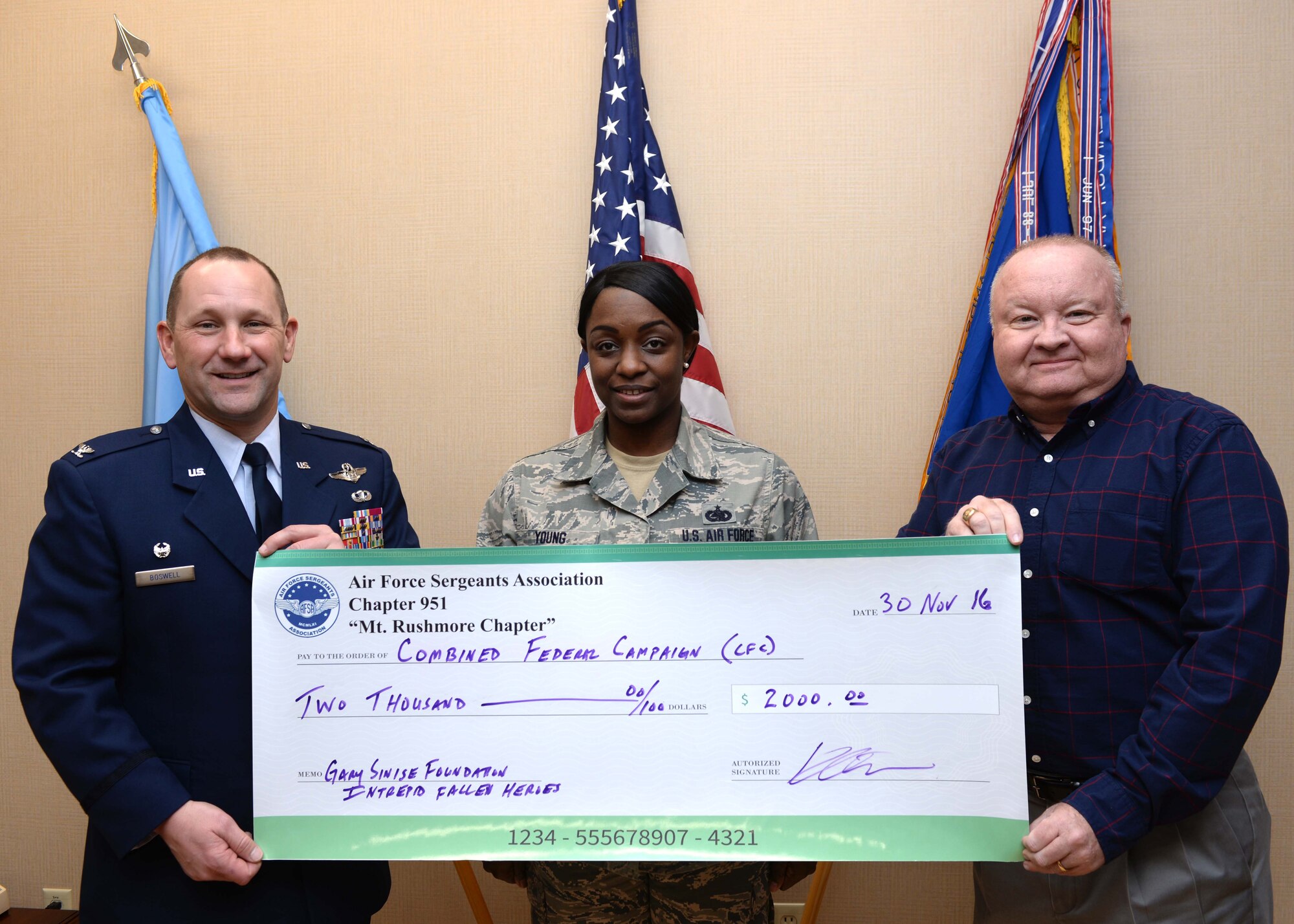 Tech Sgt. Jessica Young, non-commissioned officer in-charge of unaccompanied housing assigned to the 28th Civil Engineer Squadron, and Kevin Ott, special events coordinator, present Col. Gentry Boswell, commander of the 28th Bomb Wing, inside his office at Ellsworth Air Force Base, S.D., with a check of $2,000 in donations Nov. 30, 2016. On behalf of the Air Force Sergeants Association Chapter 951, donations were collected from members of the base to go toward the Combined Federal Campaign, the world's largest and most successful annual workplace charity campaign, with more than 130 CFCs located everywhere federal employees work. (U.S. Air Force photo by Senior Airman Anania Tekurio/Released)