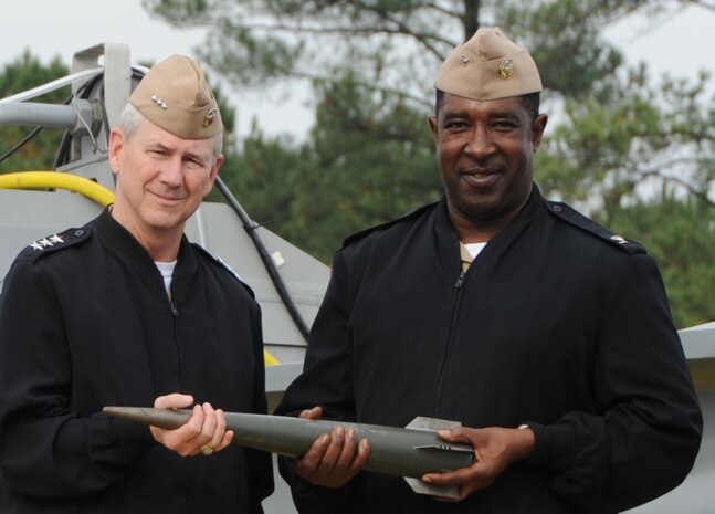 Vice Adm. Thomas Moore, commander of the Naval Sea Systems Command, left, and Capt. Godfrey "Gus" Weekes, Naval Surface Warfare Center Dahlgren Division commanding officer, hold a high velocity projectile at the electromagnetic railgun located on the Potomac River Test Range, Nov. 30. 