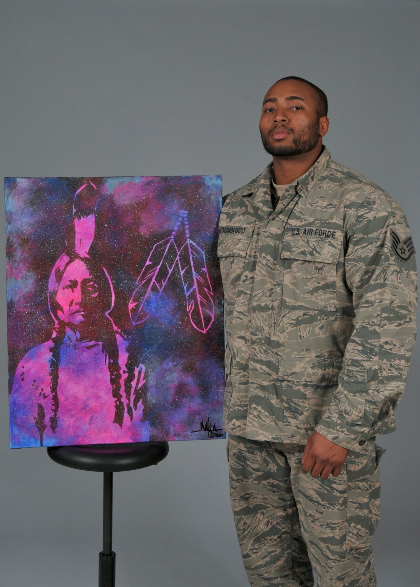 Staff Sgt. Nakoa Moonblood stands for a portrait with one of his more recent paintings Nov. 29, 2016. Moonblood recently exhibited his paintings at the Indian Summer festival in Milwaukee, Wisconsin (U.S. Air National Guard photo by Master Sgt. Kellen Kroening, 128th Air Refueling Wing Public Affairs)