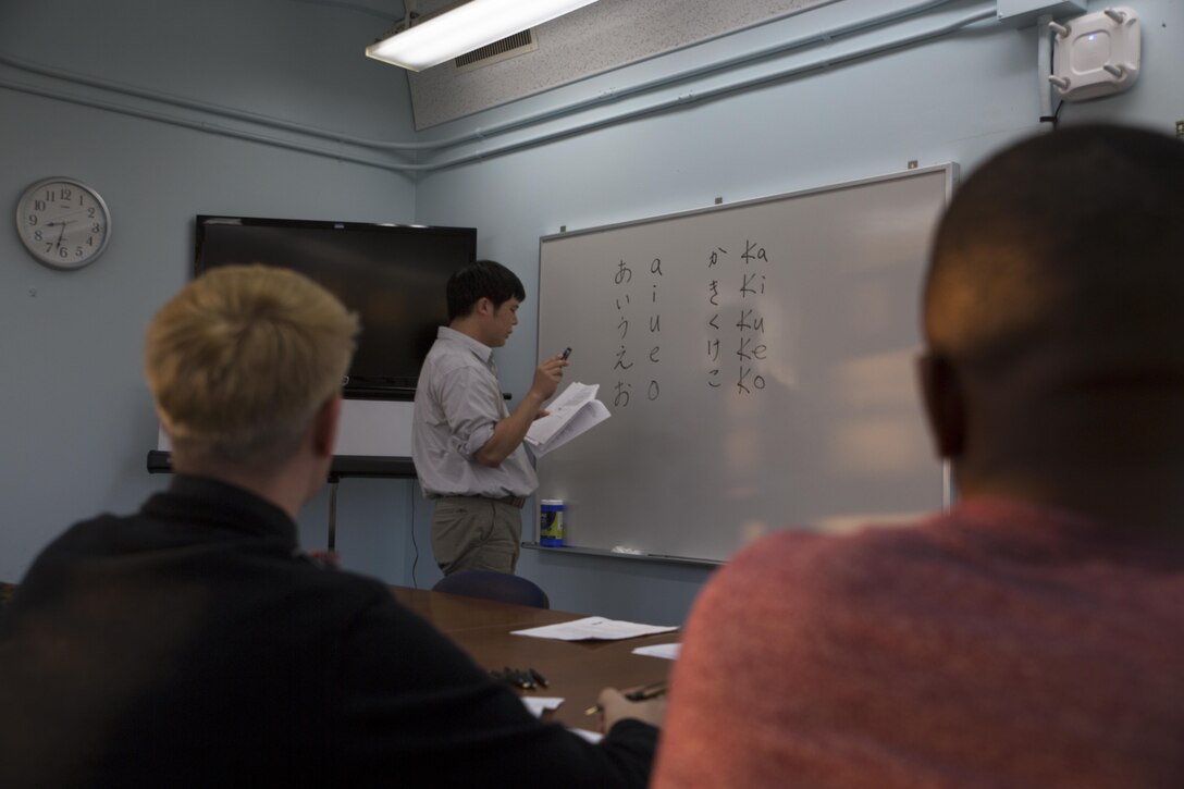 Takaatsu Sueyoshi demonstrates Japanese writing styles, which are referred to as kana, during a Survival Japanese Language class Nov. 29 on Marine Corps Air Station Futenma, Okinawa, Japan. The monthly class teaches basic principles of spoken and written Japanese in order to enrich the experiences of service members while stationed on Okinawa. The students learned about the three forms of kana, which are called hiragana, katakana and kanji and practiced writing and pronouncing the characters out loud. Sueyoshi is a library technician and the instructor of the Survival Japanese Language class. (U.S. Marine Corps photo by Cpl. Janessa K. Pon)