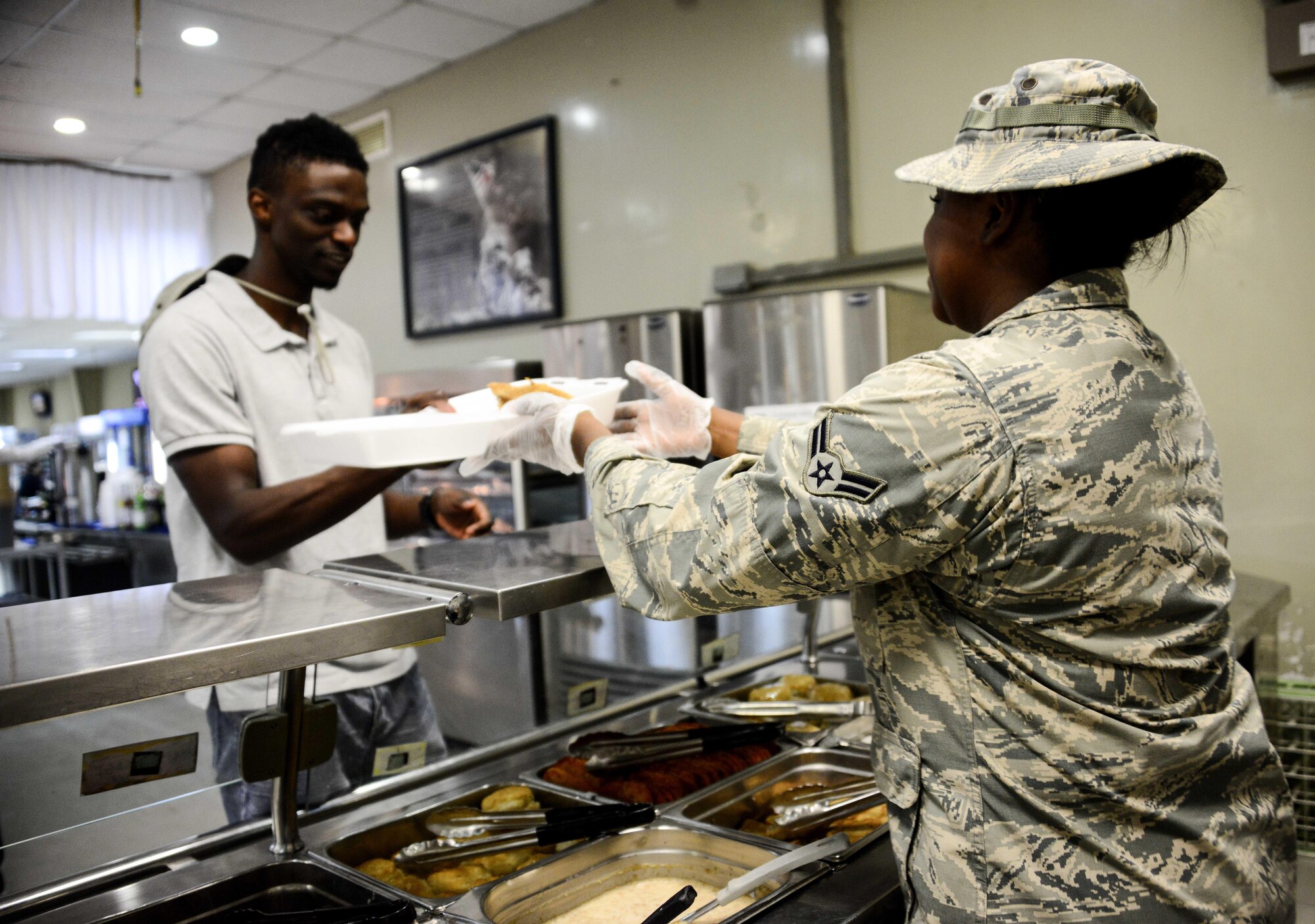 Airman 1st Class Shanette Whitehead, 379th Expeditionary Force Support Squadron service journeyman, serves a member food during the lunch meal in the Independence Dining Facility Sept. 20, 2016, at Al Udeid Air Base, Qatar. The dining facilities serve more than 500,000 meals per month, and they are supported by both contractors and EFSS personnel. (U.S. Air Force photo/Senior Airman Janelle Patiño/Released)