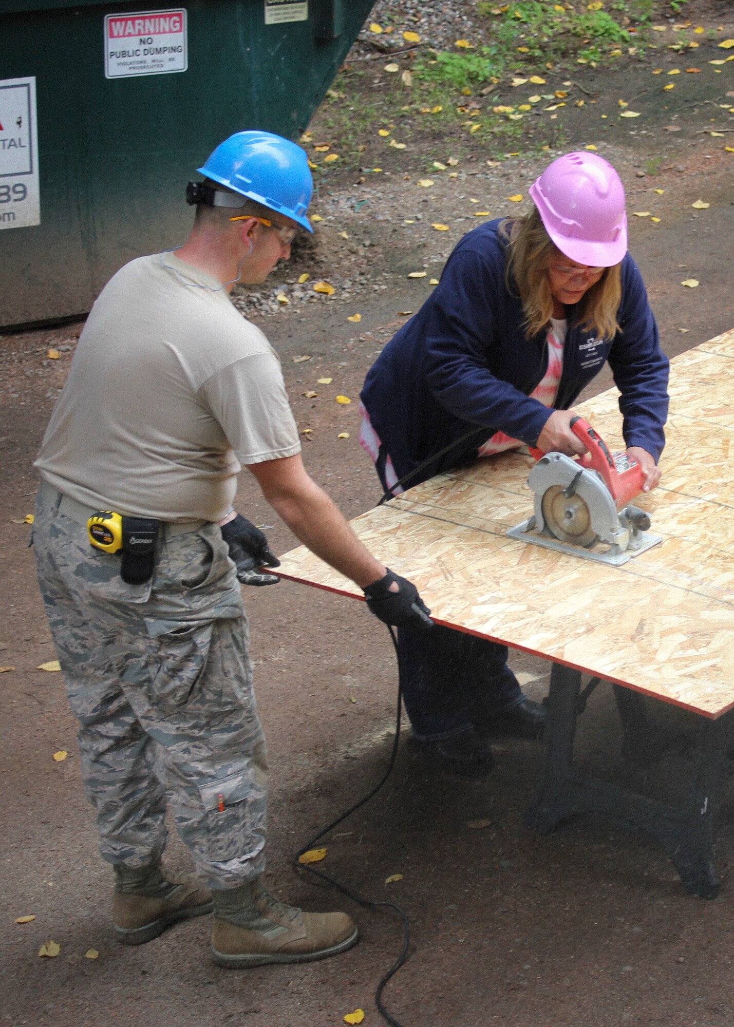An Airman with the Civil Engineer Squadron, 128th Air Refueling Wing, Wisconsin Air National Guard, works with an Oshkosh Defense employee to cut a board to its appropriate measurement Sept. 18, 2016. The 128 ARW CES Airmen worked alongside volunteers from Oshkosh Defense LLC, to build a fish-cleaning station for the camp. (U.S. Air Force photo by Senior Master Sgt. Kyle Fugar/Released)