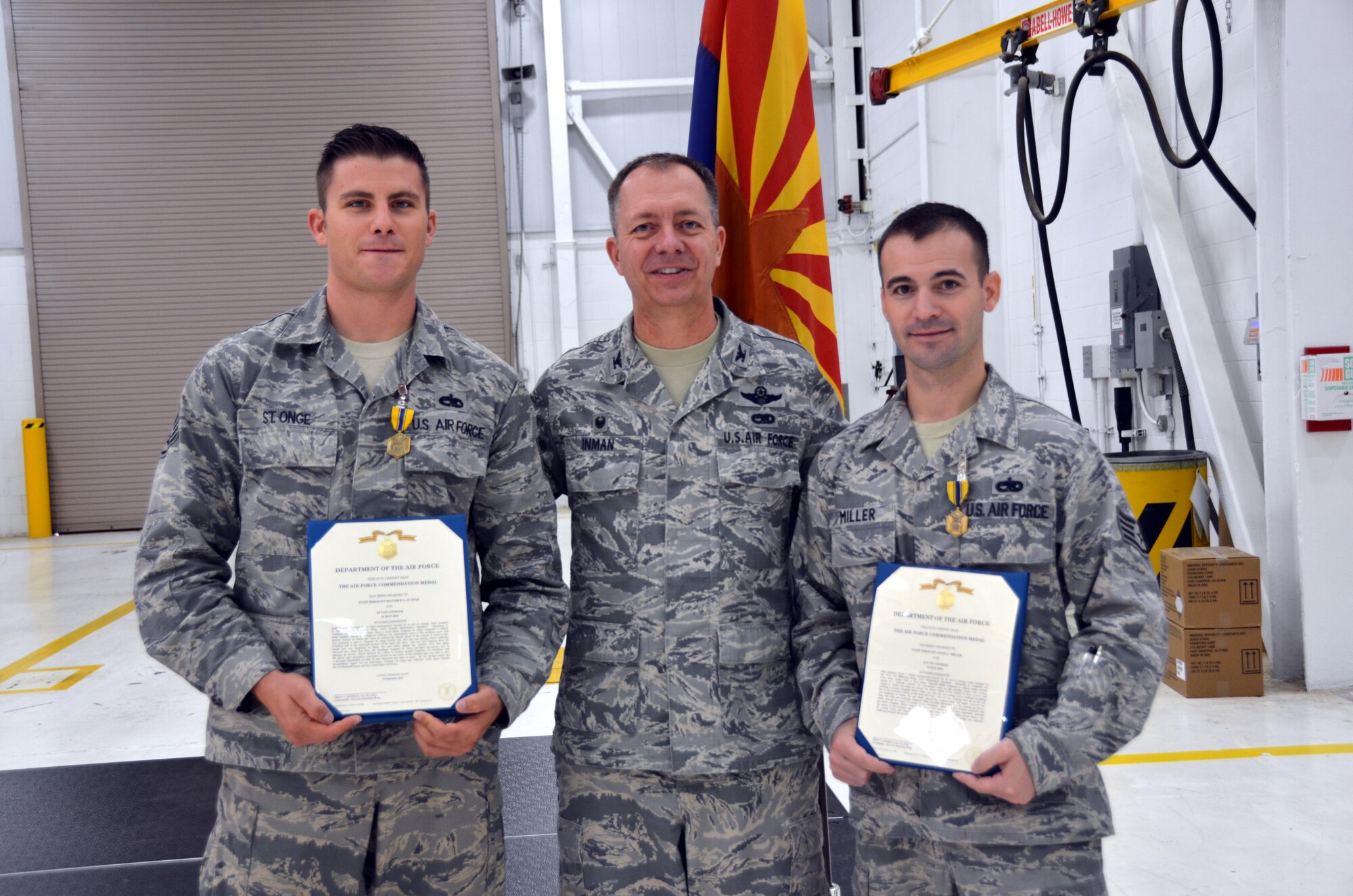 Col. Randall Inman, 161 MXG commander, presents 161st Maintenance Squadron, Staff Sgt. Matthew St. Onge, crew chief and Staff Sgt. Ancel Miller, electrical environmental specialist, with a certificate to accompany their Air Force Commendation Medals Oct., 2016, 161st Air Refueling Wing, Phoenix. The Airmen were awarded the medal for rescuing a woman after a head-on car accident. (U.S. Air National Guard photo/Tech. Sgt. Michael Matkin)