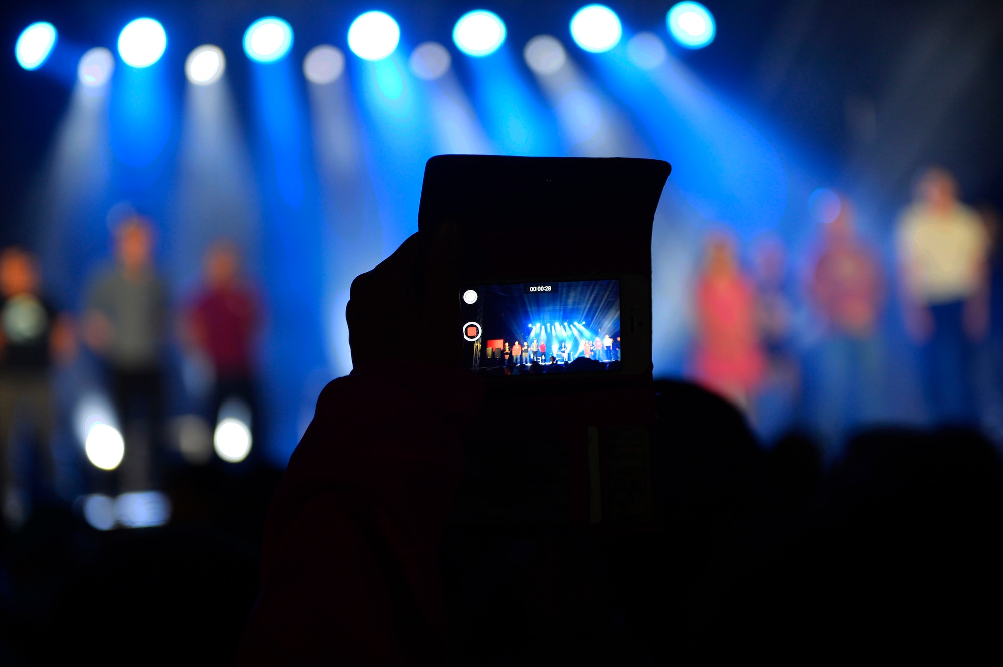 An audience member records volunteers being called on stage during a free magic show conducted by Rob Lake at Ramstein Air Base, Germany, Sept. 28, 2016. Lake invited audience members to participate in his illusions during certain portions of the show. (U.S. Air Force photo/ Airman 1st Class Joshua Magbanua)