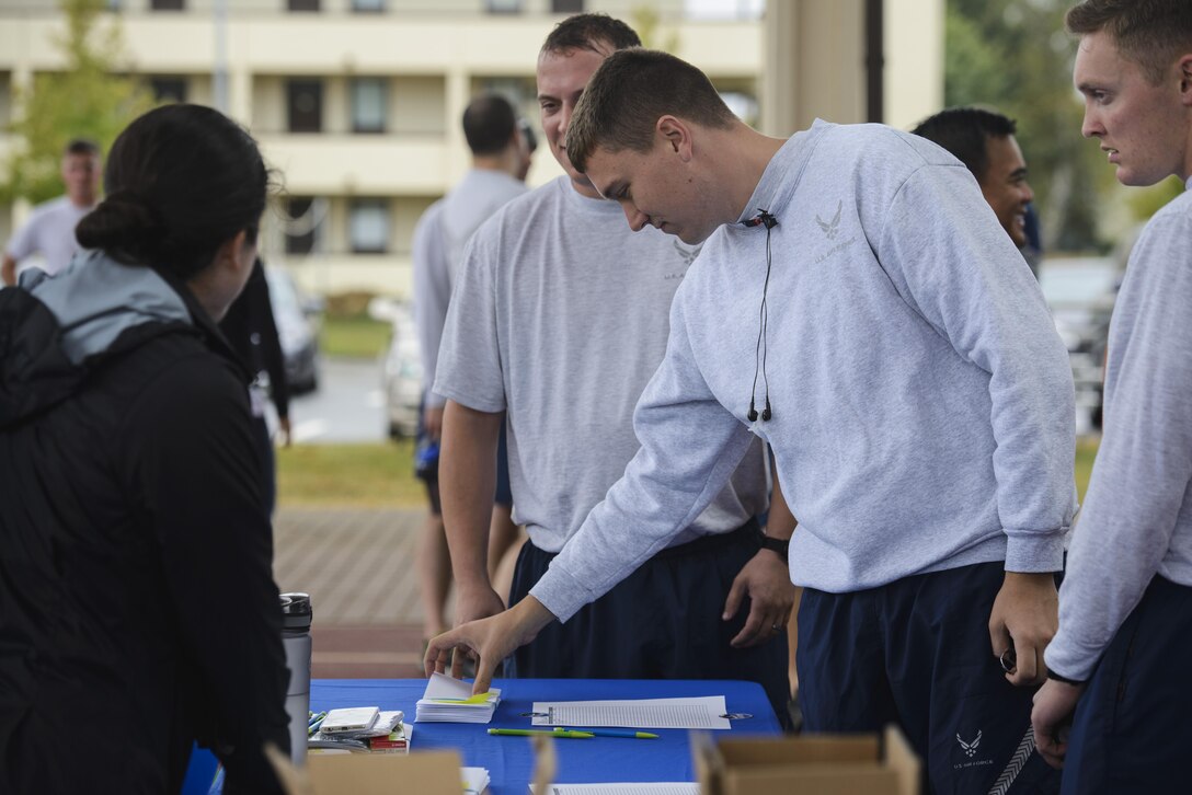 U.S. Air Force Tech. Sgt. Stephen Lynch, 52nd Civil Engineer Squadron explosive ordnance disposal craftsman, picks up his team's first clue during an Amazing Race 5k event on Spangdahlem Air Base, Germany, Sept. 30, 2016. Airmen answered questions and solved puzzles at each check point during the event based on National Preparedness Month. (U.S. Air Force photo by Staff Sgt. Jonathan Snyder)              