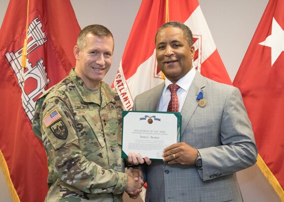 Maj. Gen. Robert Carlson presents Donn Booker with a Department of Army Meritorious Civilian Service Award during a retirement ceremony Sept. 29 in Winchester, Va.  