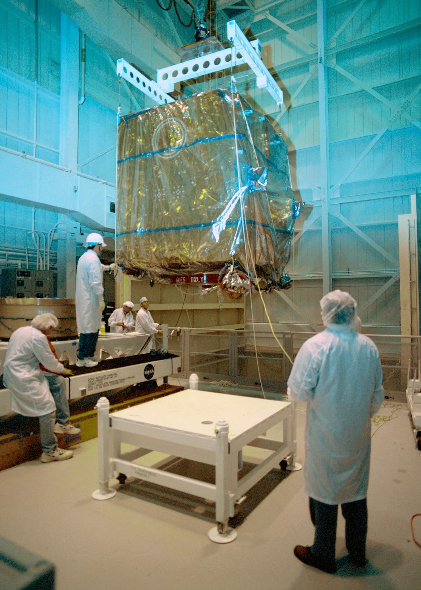 An AEDC test team prepare to hoist the Geostationary Operational Environmental Satellite-M (GOES-M) weather satellite into the clean room at the Complex Mark 1 Space Chamber in 2000. The testing at AEDC helped confirm satellite operation under simulated space conditions before it was placed in orbit. (AEDC file photo)