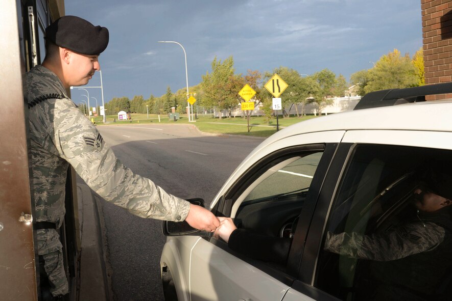 Senior Airman Tyler Serr, an installation entry controller assigned to the 5th Security Forces Squadron, hands back an ID at Minot Air Force Base, N.D., Sept. 30, 2016. Entry controllers check to verify a person’s access to a military installation through the Defense Biometrics Identification System. (U.S. Air Force photo/Airman 1st Class Jessica Weissman)