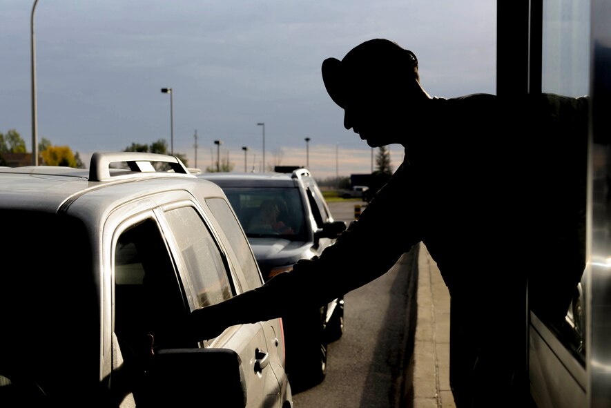 Senior Airman Tyler Serr, an installation entry controller assigned to the 5th Security Forces Squadron, hands back an ID at Minot Air Force Base, N.D., Sept. 30, 2016. Gate sentries vigilantly watch for offenses from minor vehicle infractions to personnel who may have outstanding warrants. (U.S. Air Force photo/Airman 1st Class Jessica Weissman)