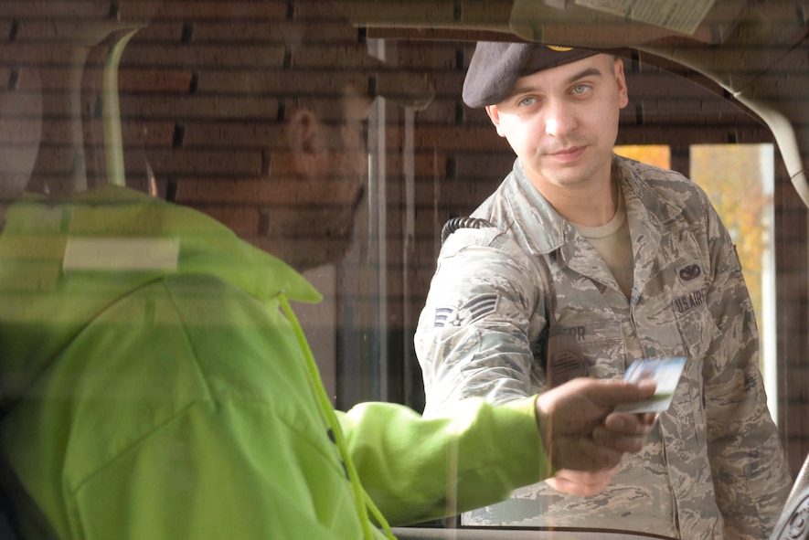 Senior Airman Tyler Serr, an installation entry controller assigned to the 5th Security Forces Squadron, hands back an ID at Minot Air Force Base, N.D., Sept. 30, 2016. Security forces members conduct random vehicle inspections and truck checks through the day and night in search of infractions. (U.S. Air Force photo/Airman 1st Class Jessica Weissman)
