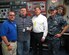 Department of Homeland Security representatives Scott Peek and Mark Boswell present a silver coin to Wes Atkinson, Naval Consolidated Brig Charleston sign shop supervisor, recognizing his many contributions to the DHS mission over the past decade Sept. 22, 2016 here. Atkinson trains prisoners in graphic design enabling them to earn Department of Labor certifications. Atkinson's design skills, project procurement knowledge and student prisoner workforce have saved the DHS over $400,000 in design and labor costs over the past 10 years. Pictured left to right, Scott Peek, Wes Atkinson, Mark Boswell, Navy Cmdr. Brett Pugsley, Naval Consolidated Brig Charleston commanding officer.