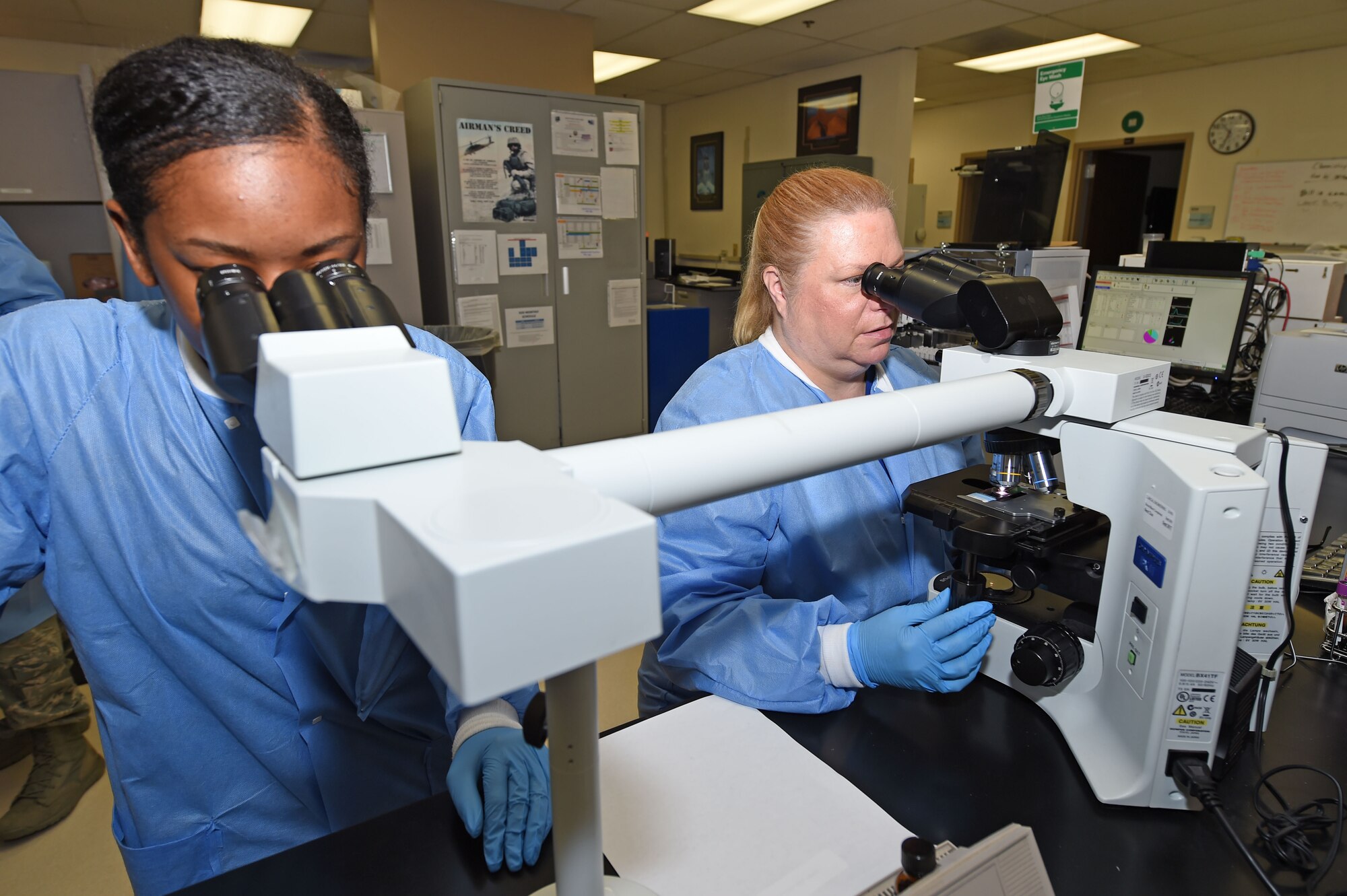 Deanna Adams and Airman 1st Class Cierra Barden, 359th Clinical Laboratory and Radiology Flight medical lab technicians, inspect a blood smear for abnormal cells with a compound microscope at the 359th Medical Group lab at Joint Base San Antonio-Randolph, Texas, Sept. 16, 2016. The compound microscope features an extra viewer to allow for training as well as simultaneous review by technicians. (U.S. Air Force photo/Tech. Sgt. Christopher Carwile/Released)