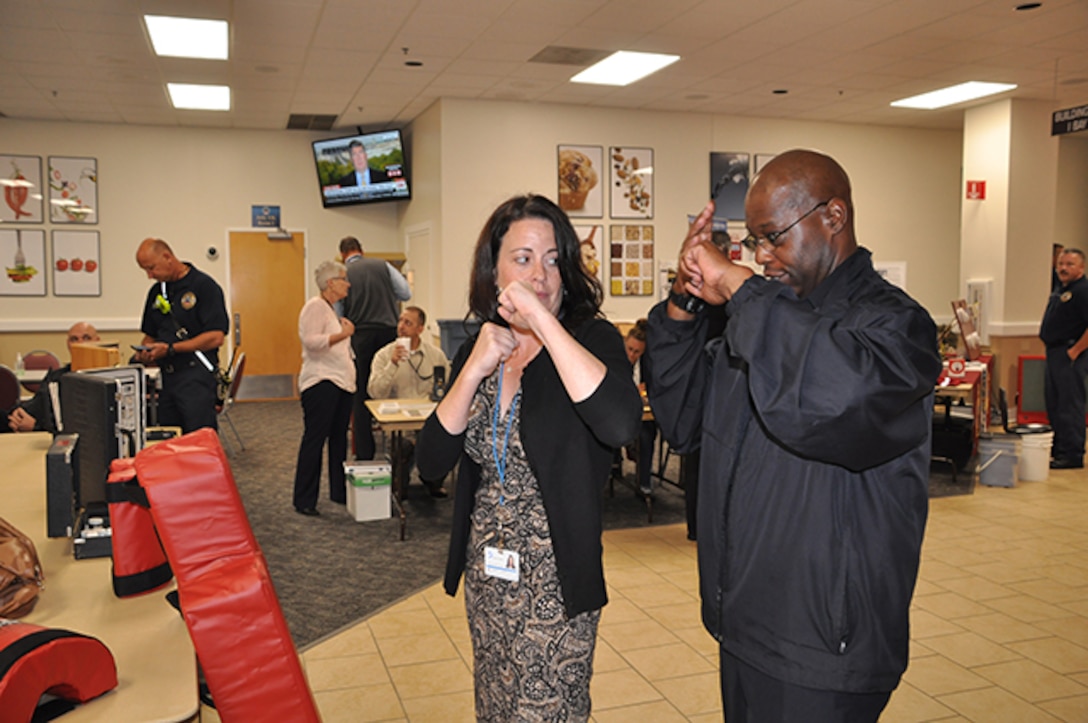 Lt. Bruce Jacobs, Defense Logistics Agency Installation Support at Richmond police training officer, shows Rebecca Bartlett, Virginia Dominion Power, safety chair, the best way to defend against an attacker during a National Preparedness Fair Sept. 28, 2016 at Defense Supply Center Richmond. Bartlett visited the fair to gain insight on conducting one for her organization. 