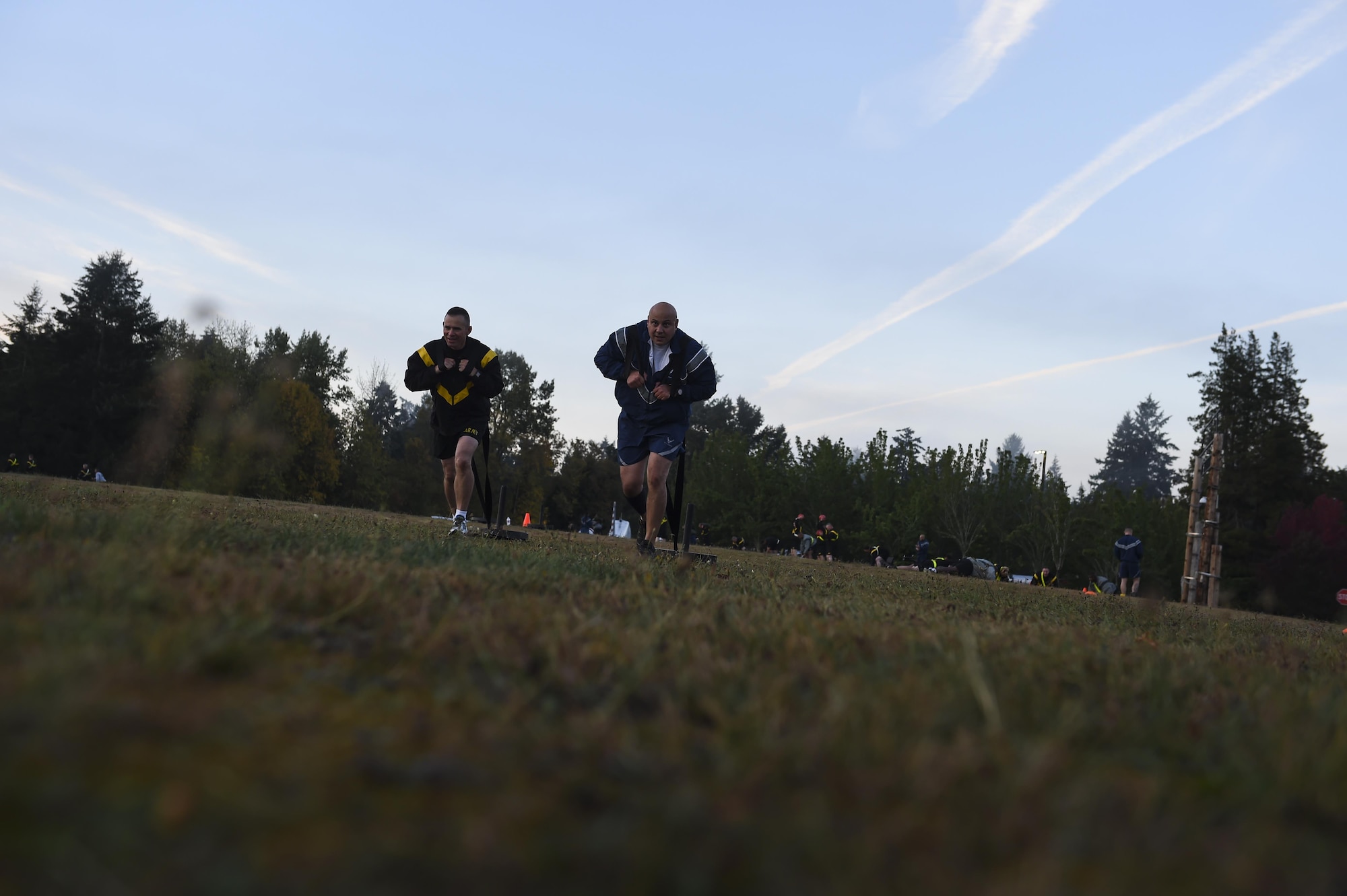 Command Sgt. Major Michael Grinston(left), 1st Corps Headquarters, and Chief Master Sgt. Tico Mazid, Airlift Wing Command Chief, drag 100 pound sleds during a Joint Base Lewis-McChord Air Force and Army Physical Training session at JBLM, Wash. The senior enlisted members at JBLM were using the joint physical training session as a team building exercise. (U.S. Air Force photo/Staff Sgt. Naomi Shipley)