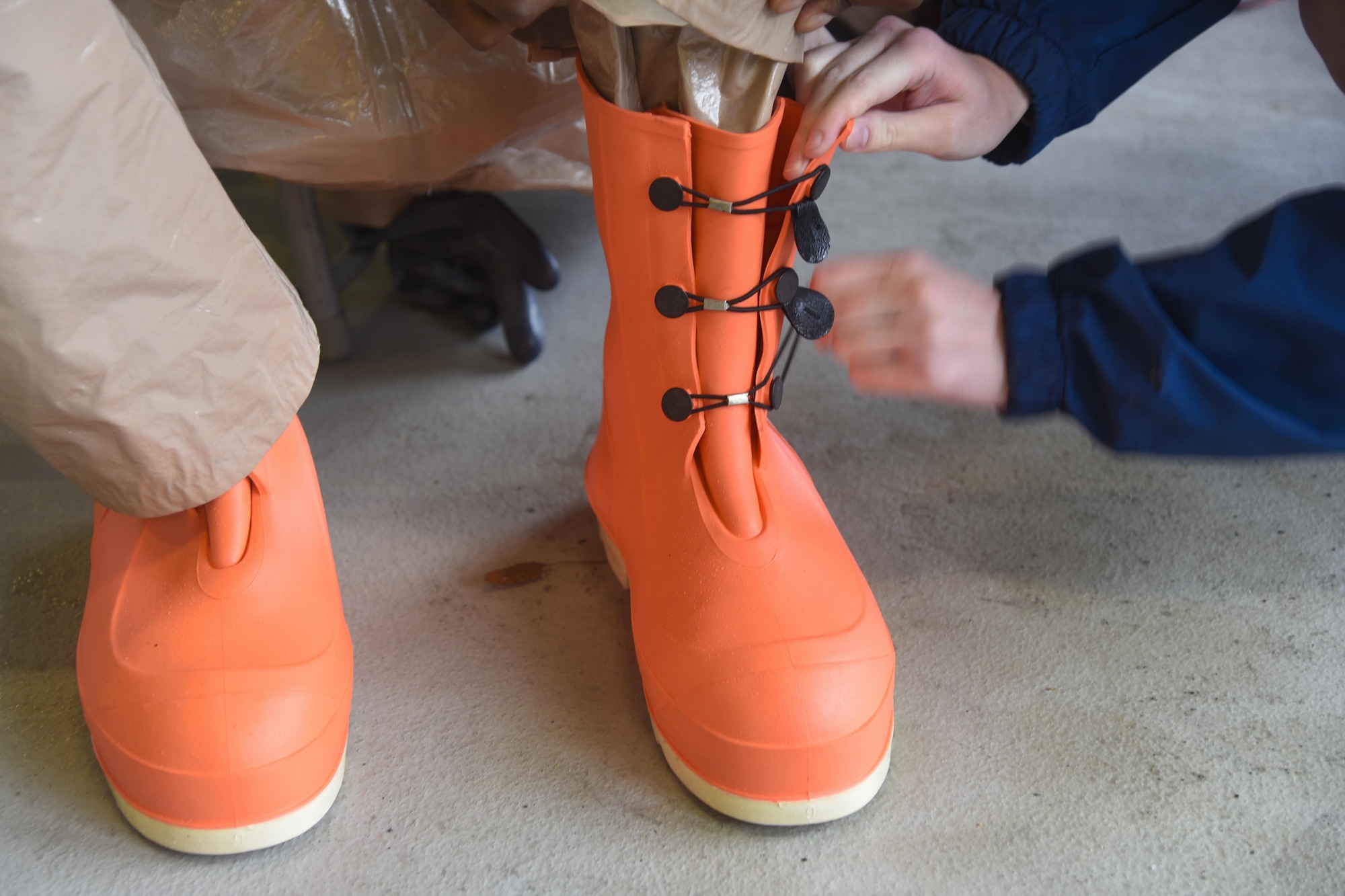 Airman 1st Class Carol Pruitt, right, 11th Civil Engineer Squadron readiness and emergency manager, tightens a boot worn by Airmen 1st Class Donnie Hamilton, 11th CES readiness and emergency manager, during hazardous material training on Joint Base Andrews, Md., Sept. 29, 2016. 11th CES prioritizes time for training so they are ready to respond to any HAZMAT leak or spill. The training required a specific uniform which included rubber boots, zip lock sealed suits and oxygen masks. (U.S. Air Force photo by Airman 1st Class Valentina Lopez)