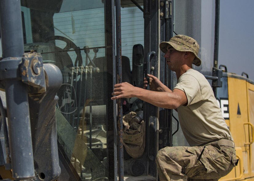 Senior Airman Austin DeDeo, 455th Expeditionary Civil Engineer Squadron pavements and heavy equipment technician, climbs into a motor grader, Bagram Airfield, Afghanistan, Oct. 4, 2016. The ECES “Dirt Boys”, as they are known, laid down gravel to start the foundation for a new road. The road, which will provide a pathway for mine-resistant ambush-protected (MRAP) vehicles, will be built around the fence line of the airfield and utilized by security forces as a means to secure the flightline. (U.S. Air Force photo by Senior Airman Justyn M. Freeman)