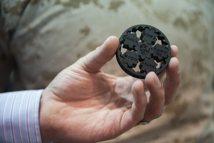 160928-N-IL267-002 QUANTICO, Virginia (Sept. 28, 2016) Jonathan Hopkins, a member of the Additive Manufacturing Tiger Team and employee of Naval Surface Warfare Center, Carderock Division, holds up a 3-D printed symbol at the Modern Day Marine Expo at Marine Corps Base Quantico, Va. This symbol represents Naval Sea Systems Command, Naval Aviation Systems Command, Marine Corps Systems Command, the Marine Corps Warfighting Laboratory, and Marine Corps Headquarters, Installations and Logistics Department, all of which collaborated on an additive manufacturing parts demonstration at the expo. (U.S. Navy photo by Dustin Q. Diaz/released)