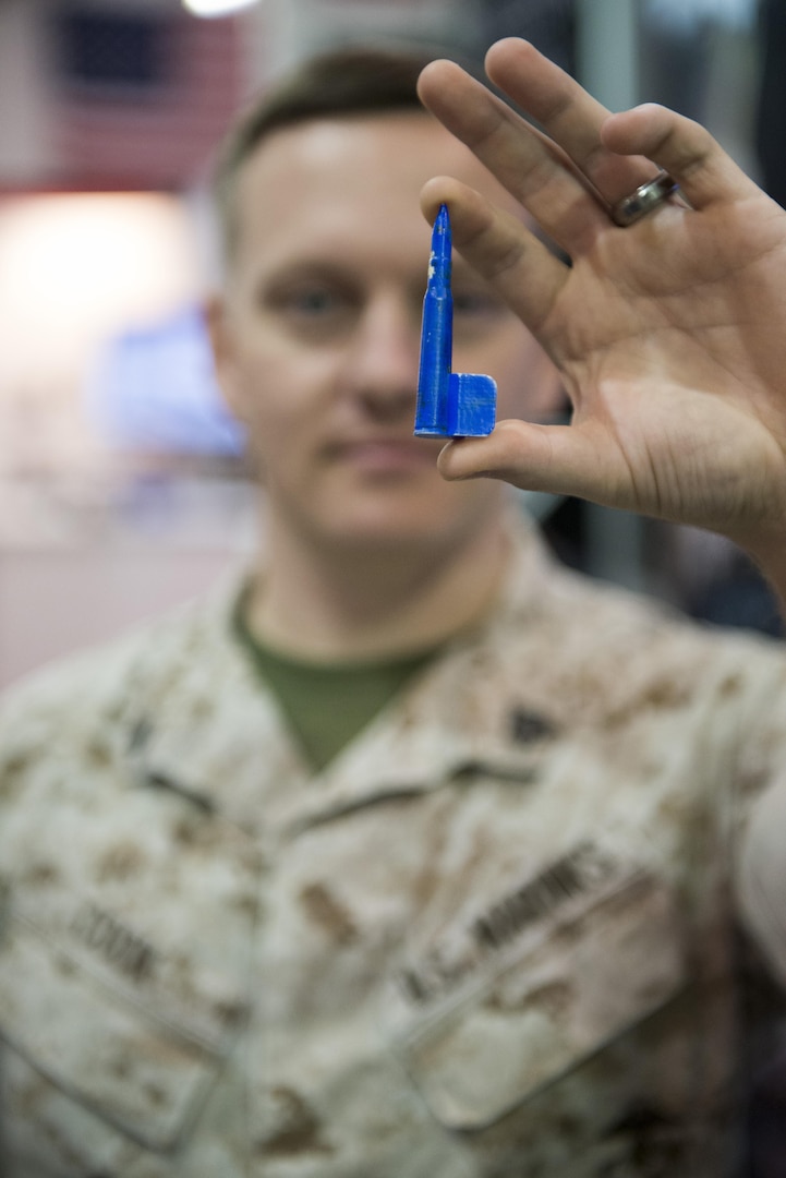 160928-N-IL267-004 QUANTICO, Virginia (Sept. 28, 2016) Marine Sgt. Stephen Cook, a legal service specialist with Headquarters Marine Corps, Judge Advocate Division, and amateur hobbyist 3-D printer, holds up a water cooler spigot in the shape of a rifle round that he printed using additive manufacturing to replace one that had broken at his office during the Modern Day Marine Expo at Marine Corps Base Quantico, Va. Cook is sharing his 3-D printing expertise during an additive manufacturing parts demonstration at the expo, which Naval Sea Systems Command, Naval Aviation Systems Command, Marine Corps Systems Command, the Marine Corps Warfighting Laboratory, and Marine Corps Headquarters, Installations and Logistics Department all collaborated on. (U.S. Navy photo by Dustin Q. Diaz/released)