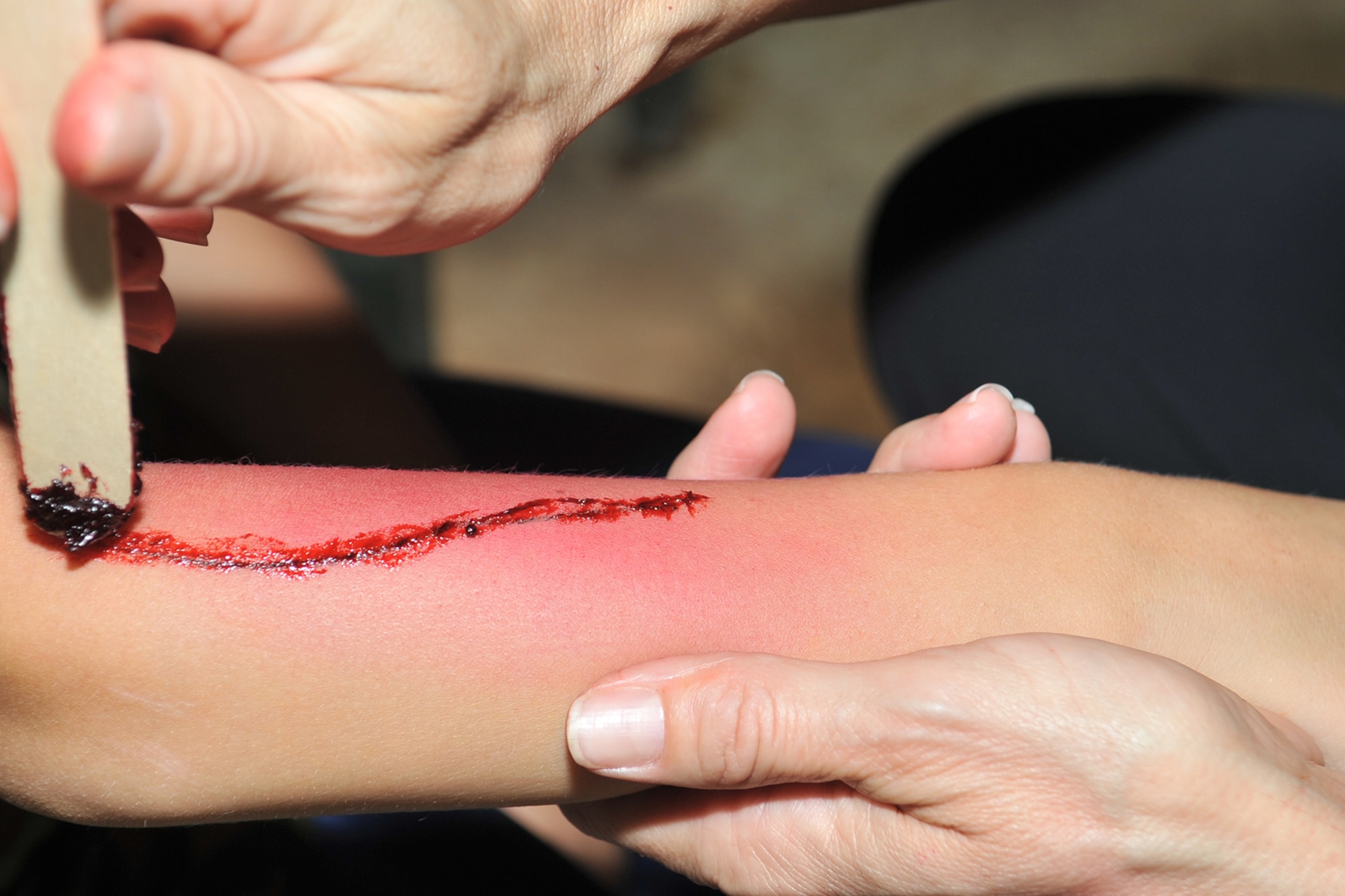 Cecilia Diaz, 17th Medical Group Family Advocacy outreach manager, paints a child’s arm to look like an injury during Operation Kids Investigating Deployment Services at Camp Sentinel, Goodfellow Air Force Base, Texas, Oct. 1, 2016. The wound painting technique is called moulage and is used for the purpose of training emergency response teams and other medical and military personnel. (U.S. Air Force photo by Staff Sgt. Laura R. McFarlane/Released)