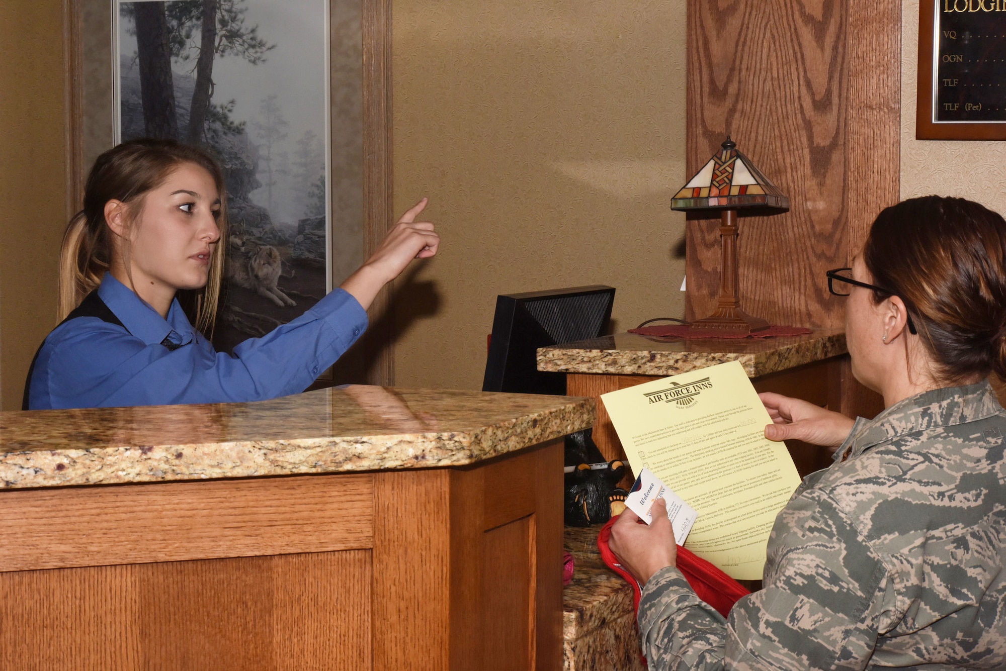 Katelyn Brooks, Malmstrom Inn desk services representative, assists a guest to check in at the inn at Malmstrom Air Force Base, Mont., Sept. 23, 2016.  The 83-room lodging facility has units available for active duty and retired Department of Defense members and their families.  (U.S. Air Force photo/Jason Heavner)  