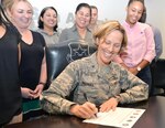 Brig. Gen. Heather L. Pringle, 502nd Air Base Wing and Joint Base San Antonio commander, signs a proclamation designating October as Domestic Violence Awareness Month Sept. 13 in the JBSA-Fort Sam Houston conference room, surrounded by members of the JBSA Family Advocacy staff.