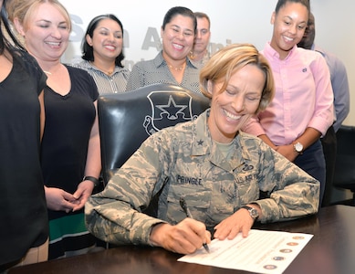 Brig. Gen. Heather L. Pringle, 502nd Air Base Wing and Joint Base San Antonio commander, signs a proclamation designating October as Domestic Violence Awareness Month Sept. 13 in the JBSA-Fort Sam Houston conference room, surrounded by members of the JBSA Family Advocacy staff.