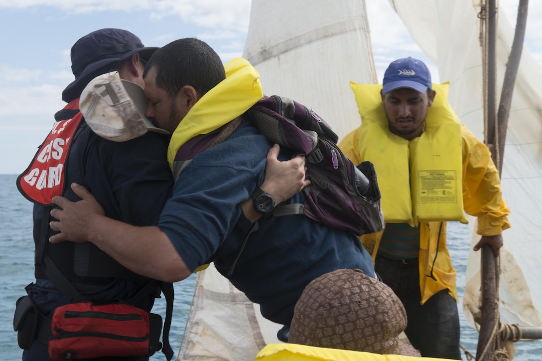 Coast Guard Petty Officer 1st Class Jorge Canedo, a certified Spanish interpreter and crewmember aboard the Coast Guard Cutter Kathleen Moore, assists a Cuban man to a Coast Guard small boat in the Caribbean Sea, Dec. 9, 2015. In the course of three days the crew of the Kathleen Moore interdicted 50 Cuban migrants allegedly attempting to enter the U.S. illegally. (U.S. Coast Guard photo by Petty Officer 3rd Class Ashley J. Johnson)