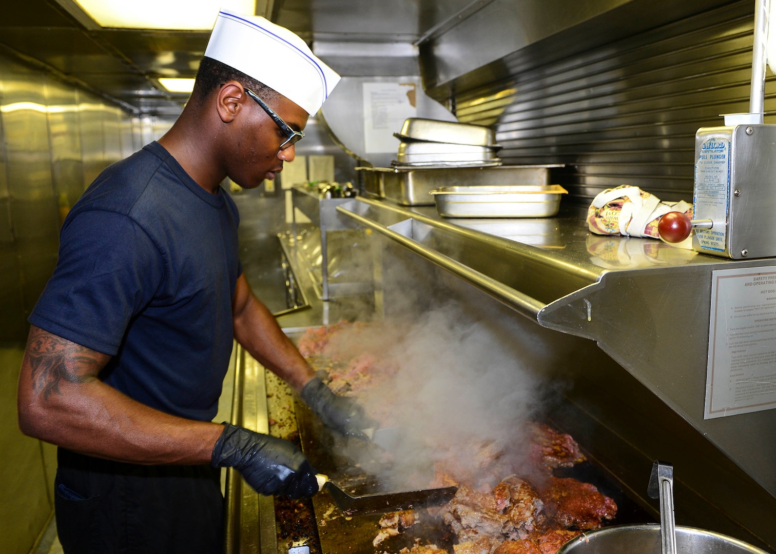 Navy Culinary Specialist 3rd Class Traivon Smart grills meat in the galley aboard the amphibious dock landing ship USS Whidbey Island (LSD 41) Aug. 9. DLA Troop Support's Subsistence supply chain hosted a pre-proposal conference Sept. 28 to help vendors preparing proposals for an upcoming beef national contract