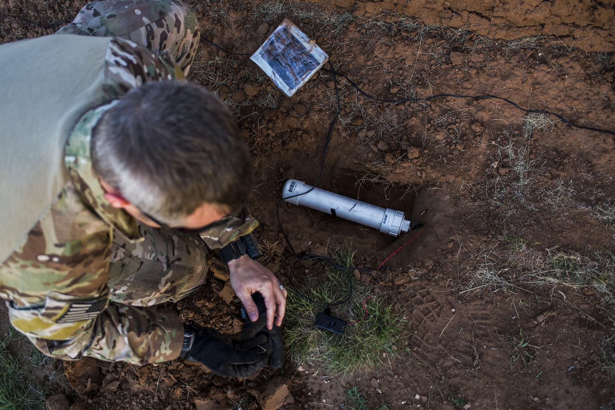 Master Sgt. Jeremy Phillips, 27th Special Operations Civil Engineer Squadron Explosive Ordnance Disposal flight chief, places a simulated improvised explosive device in the ground during IED training at Melrose Air Force Range, N.M., Sept. 28, 2016. An IED is any bomb constructed and deployed in other ways than conventional military methods and commonly used as a roadside bomb. (U.S. Air Force photo by Senior Airman Luke Kitterman/Released)