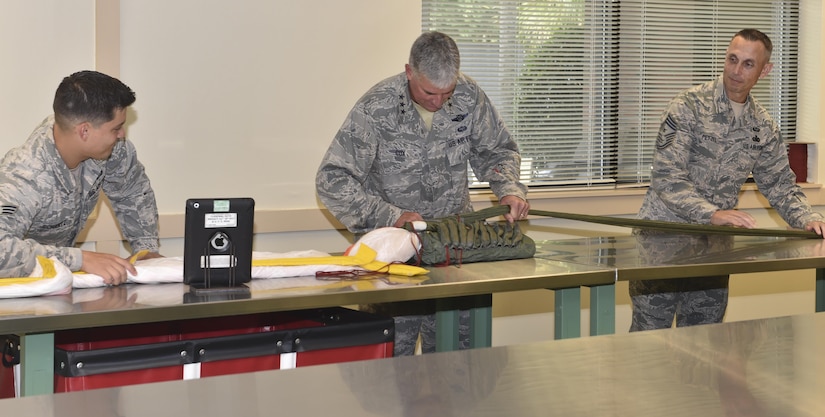 Senior Airman Brian Schantz, Aircrew Flight Equipment, teaches  Lt. Gen. Sam Cox, 18th Air Force commander, and Chief Master Sgt. Todd Petzel, command chief of the 18th Air Force, to pack a parachute September 29, 2016, at Joint Base Charleston, South Carolina. One Aircrew Flight Equipment technician and up to two trainees are responsible for packing 25 parachutes every month in support of flight operations.