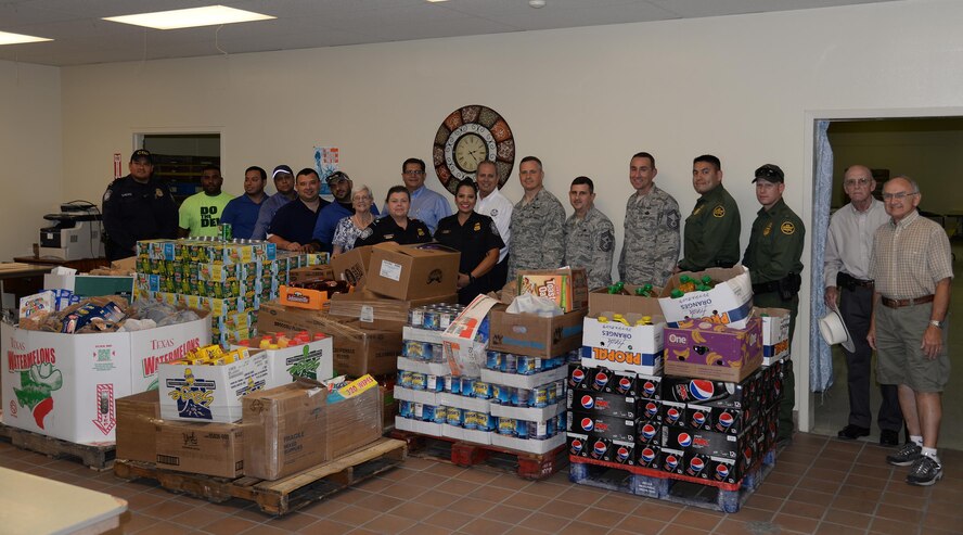Col. Thatcher Cardon, 47th Medical Group commander, and Chief Master Sgt. George Richey, 47th Flying Training Wing command chief, pose with community leaders, volunteers and Val Verde Loaves and Fishes food pantry staff in front of food donated as part of the Feds Feed Families campaign in Del Rio, Texas, Sept. 28, 2016. Cardon and Richey were on hand to celebrate the handover of more than 10,000 pounds of non-perishable food items collected by the men and women of Laughlin Air Force Base and Border Patrol and Customs for the local food bank, which helps feed approximately 18,000 families in and around Del Rio each year. (U.S Air Force photo/Joel Langton)