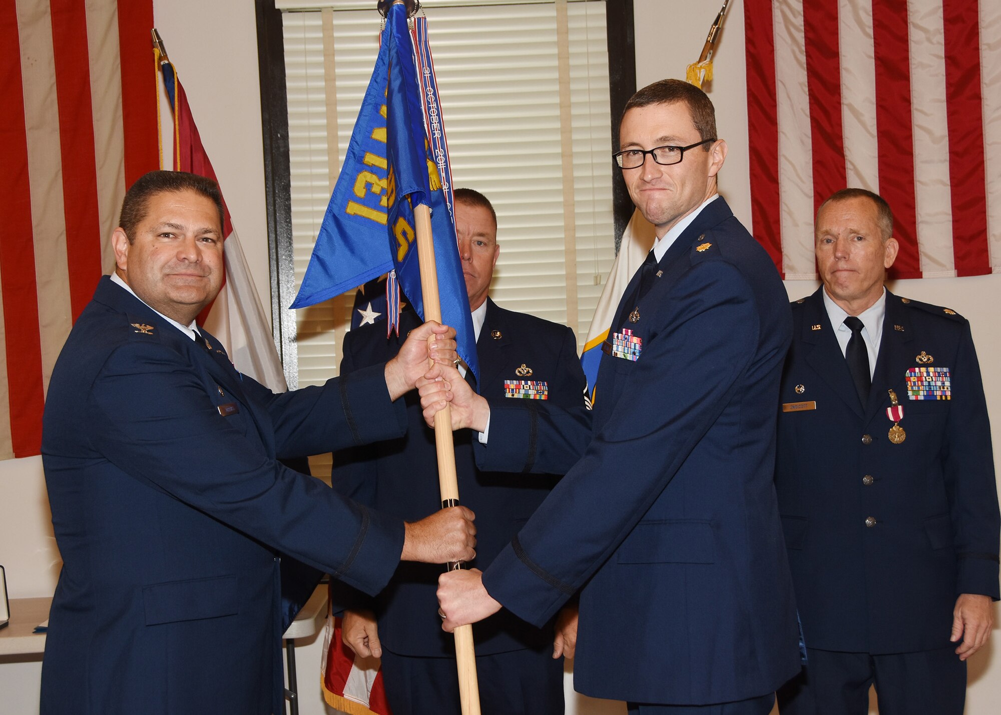 While outgoing commander Lt. Col. Lane Endicott stands by, Maj. Daniel Nelsen accepts the 131st Civil Engineers Squadron guidon from 131st Bomb Wing Mission Support Group commander Col. Mike Jurries. The change of command ceremony was held at Jefferson Barracks Air National Guard Base, Missouri, Oct 1, 2016. (U.S. Air National Guard photo by Senior Master Sgt. Mary-Dale Amison)