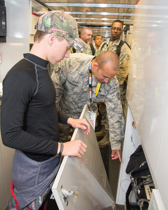 Brandon Jones driver of the No. 33 Nexteer Chevy Camaro, shows Team Dover Airmen a spare engine stored on his racecar trailer during the Troops to Tracks program Oct. 1, 2016, at Dover International Speedway, Del. Troops to Track gives fans, with a military tie, behind-the-scenes tours at NASCAR events. (U.S. Air Force photo by Mauricio Campino)