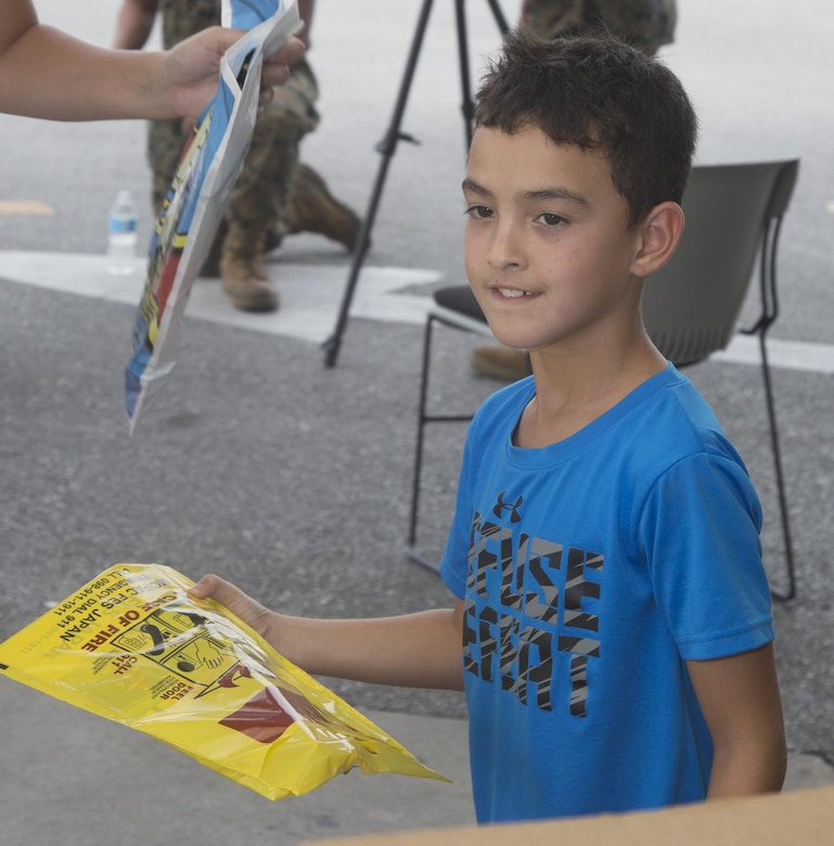 A child takes a handout from the Emergency Awareness Day booth at the commissary on Camp Foster, Okinawa, Sept. 27, 2016. Emergency Awareness Day intends to increase the knowledge of the community by alerting people and providing them with a better understanding of the actions that need to be taken in the case of emergency. (U.S. Marine Corps photo by MCIPAC Combat Camera PFC. Damion Hatch JR/Released)    