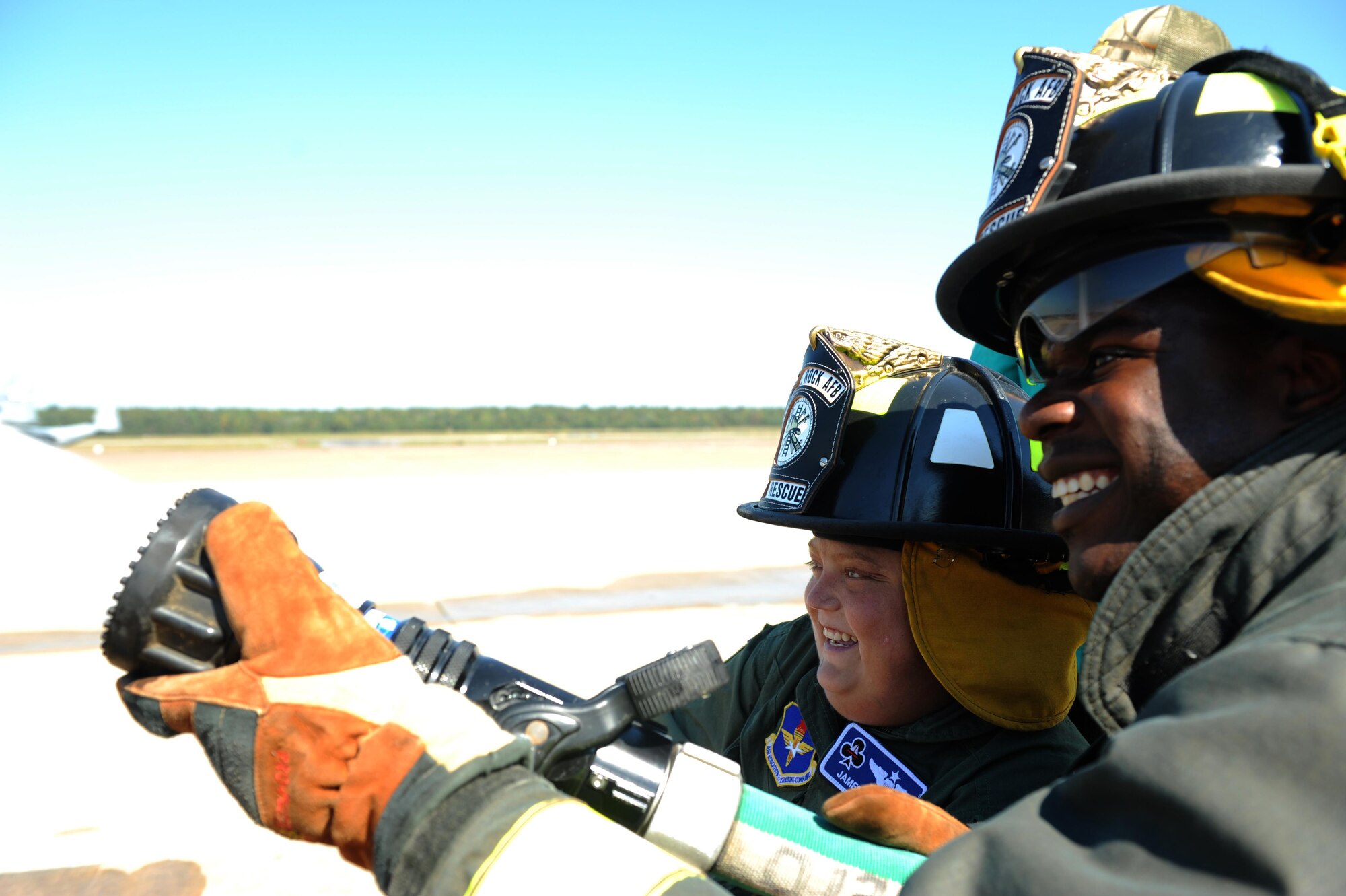 (From right) U.S. Air Force Senior Airman Marcus Scriven, 19th Mission Support Group Fire Department firefighter, helps James Rogers, 17, operate the fire hose during his tour of the fire department Oct. 3, 2016, at Little Rock Air Force Base, Ark. Rogers received the tour as part of the Pilot for a Day program, which provides children who have serious or chronic illnesses an opportunity to be part of a flying squadron for an entire day. 