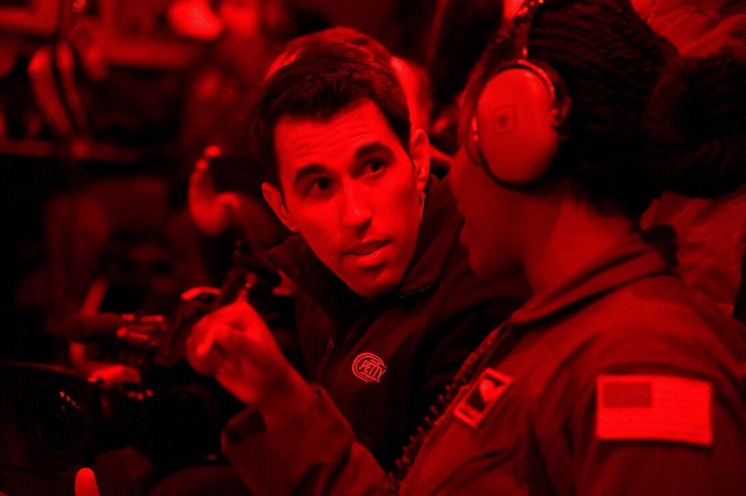 Using red cargo compartment lights for low-light operations, Aric Almirola, NASCAR Sprint Cup Series driver for the No. 43 Smithfield Ford, left, speaks with Senior Airman Toiannah Campbell, 3d Airlift Squadron loadmaster, as the C-17A Globemaster III taxis into position for a combat offload demonstration Sept. 29, 2016, on Dover Air Force Base, Del. More than 40 NASCAR orientation flight participants including Almirola, observed the Globemaster III being air refueled by a KC-135R Stratotanker from the 459th Air Refueling Wing, Joint Base Andrews, Md., during the 2.2-hour flight. (U.S. Air Force photo by Roland Balik)