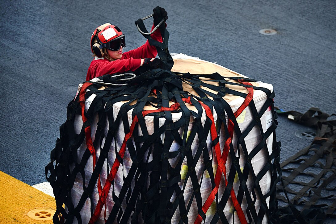 A sailor takes the netting off cargo during a vertical replenishment aboard the amphibious assault ship USS Bataan in the Atlantic Ocean, Oct. 1, 2016. Navy photo by Petty Officer 1st Class Julie R. Matyascik