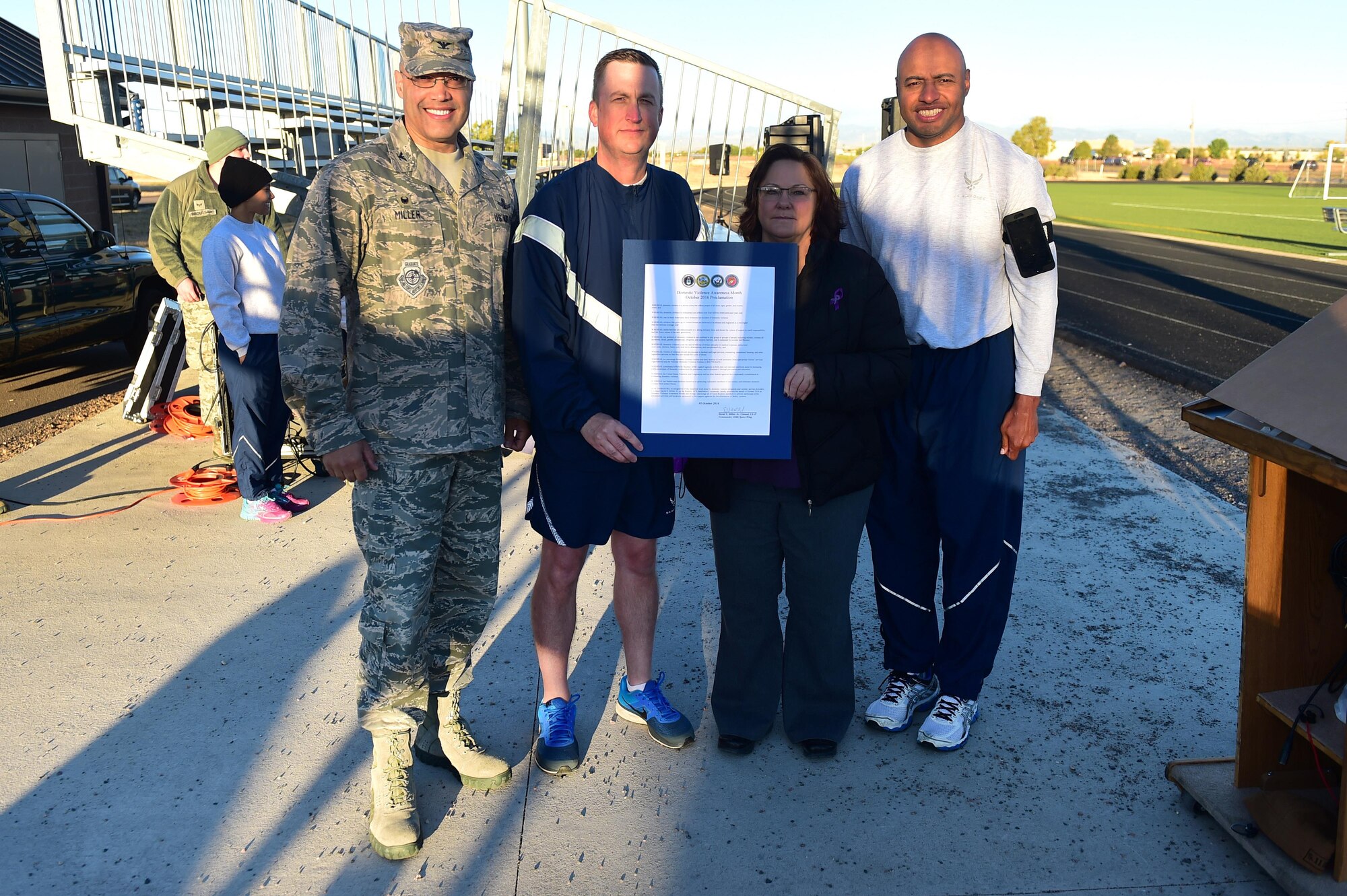 Buckley Air Force Base leadership stands with a domestic violence proclamation before a Domestic Violence Awareness Month 5K Run/Walk Oct. 5, 2016, at the outdoor track on Buckley Air Force Base, Colo. National Domestic Violence Awareness Month aims to make America a country where no one suffers the hurt and hardship that domestic violence causes. (U.S. Air Force photo by Airman 1st Class Gabrielle Spradling/Released)