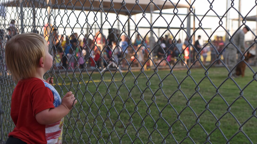 Keegan Davis watches 7th Security Forces Squadron military working dog handlers perform a K-9 demonstration during National Night Out, at Dyess Air Force Base, Texas, Oct. 4, 2016. NNO was established to provide an opportunity for police and neighbors to come together under positive circumstances to make neighborhoods safer and better places to live. (U.S. Air Force photo by Senior Airman Kedesha Pennant)
 
