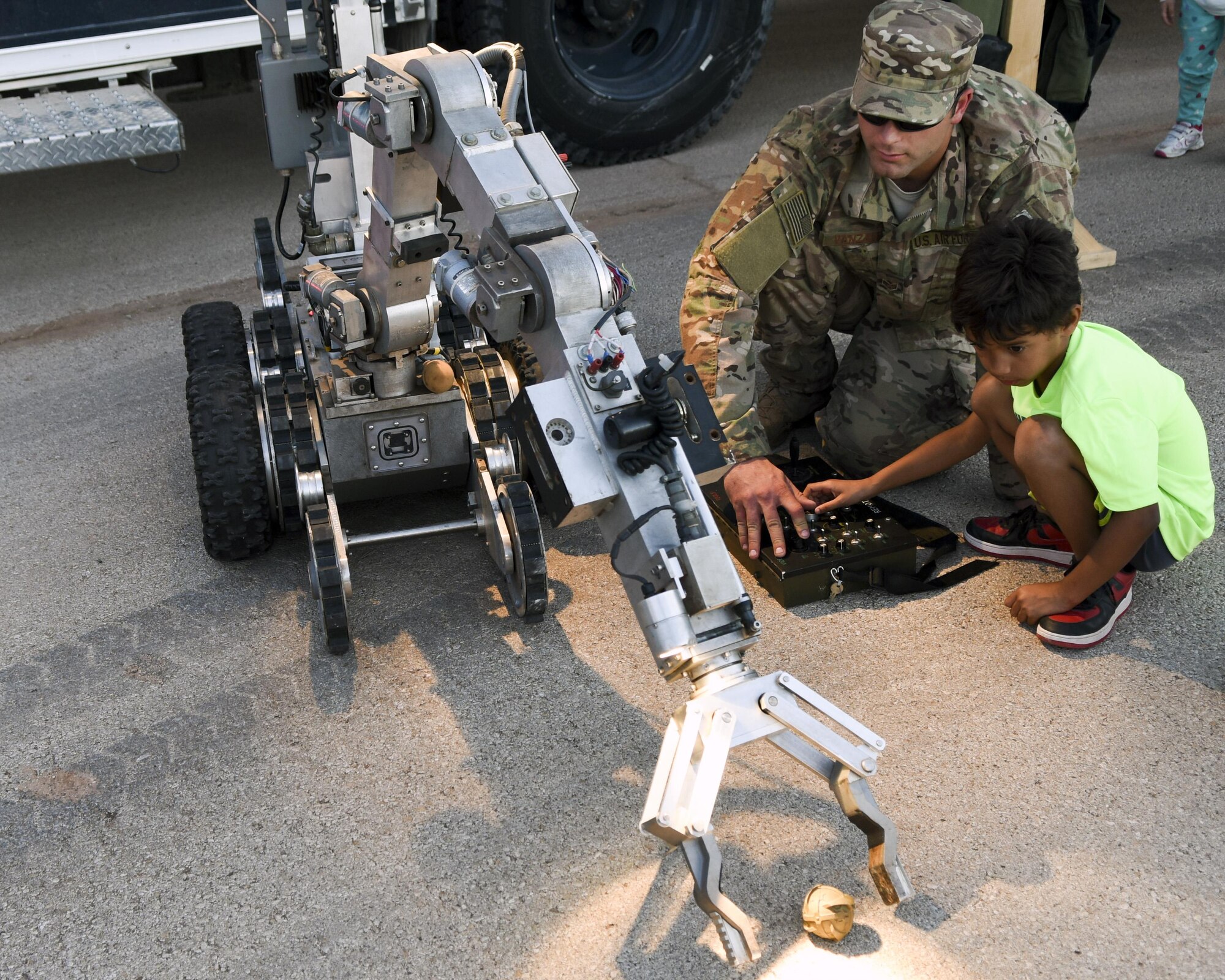 U.S. Air Force Senior Airman Bryce Vanzale, 7th Civil Engineer Squadron explosive ordinance disposal technician, instructs David Whorton on how to operate an F6A robot during National Night Out, at Dyess Air Force Base, Texas, Oct. 4, 2016. EOD uses F6A robots to survey any improvised explosive devices or unexploded ordnance to ensure a safe and successful outcome for their missions. (U.S. Air Force photo by Senior Airman Kedesha Pennant)