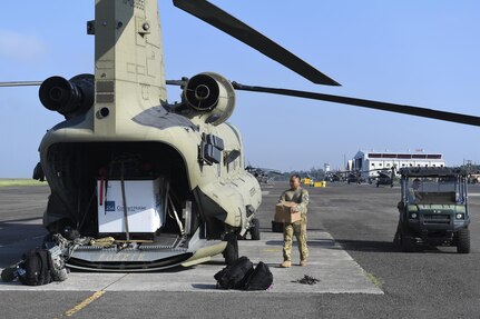 A CH-47 Chinook helicopter crew chief assigned to Joint Task Force-Bravo’s 1st Battalion, 228th Aviation Regiment, prepares to a load a box at Soto Cano Air Base, Honduras, Oct. 5, 2016, in preparation for a flight to the Grand Cayman Islands and eventually on to Haiti to provide airlift capabilities for Hurricane Matthew relief efforts as requested by the U.S. Agency for International Development’s Office of Foreign Disaster Assistance. The mission of Joint Task Force-Bravo includes being prepared to support disaster relief operations in Central America, South America and the Caribbean, when directed by SOUTHCOM. (U.S. Air Force photo by Staff Sgt. Siuta B. Ika)