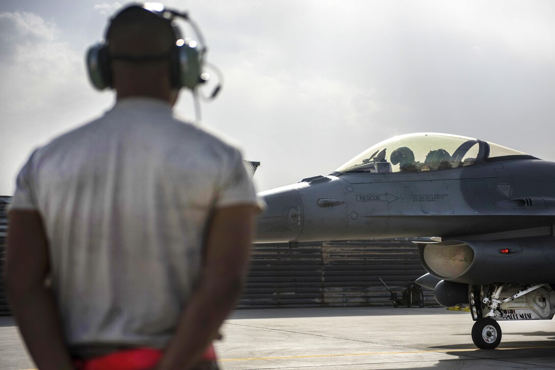 Air Force Senior Airman Jean Alonso waits to marshal an F-16C Fighting Falcon aircraft at Bagram Airfield, Afghanistan, Oct. 5, 2016. Alonso is a crew chief assigned to the 455th Expeditionary Aircraft Maintenance Squadron. The crew chiefs are the aircraft caretakers, inspecting and preparing aircraft they are ready to fly at a moment’s notice. Air Force photo by Senior Airman Justyn M. Freeman