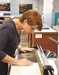 Penny Latimer, electronic duplicating system technician at Fort Riley, cuts a straight edge on a poster Sept. 22 at Defense Logistics Agency Document Services, 263 Cameron Ave.
