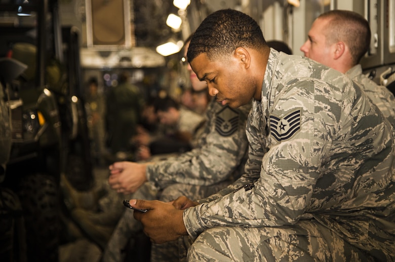 An Airmen assigned to the 621st Contingency Response Wing passes the time by playing with his phone as the C-17 Globemaster III he is sitting in is loaded with equipment at Joint Base McGuire-Dix-Lakehurst, N.J. October 6, 2016. The Airmen are on their way to Port-au-Prince, Haiti, in response to Hurricane Matthew. The CRW is highly-specialized in rapidly deploying personnel to quickly open airfields and establish, expand, sustain, and coordinate air mobility operations alongside joint and intra-agency partners. (U.S. Air Force photo by Tech. Sgt. Gustavo Gonzalez/Released)