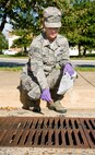 Airman 1st Class Jamie Tstinic, 436th Civil Engineering Squadron pest control apprentice, gets ready to drop a packet of VectoLex WSP into a storm drain with standing water present Oct. 6, 2016, in the Dover Family Housing area, Dover Air Force Base, Del. Tstinic and other members of the 436th CES Entomology section placed numerous 10-gram packets of VectoLex WSP, a selective microbial insecticide, anywhere standing water was present that could possibly contain mosquito larva known to carry the West Nile Virus. (U.S. Air Force photo by Roland Balik)