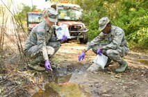 Airman 1st Class Jamie Tstinic, and Airman 1st Class Harry Landry, both 436th Civil Engineering Squadron pest control apprentices, prepare to place packets of VectoLex WSP into a puddle of standing water Oct. 6, 2016, in the Dover Family Housing area, Dover Air Force Base, Del. Tstinic, Landry and other members of the 436th CES Entomology section placed numerous 10-gram packets of VectoLex WSP, anywhere standing water was present that could possibly contain mosquito larva known to carry the West Nile Virus. (U.S. Air Force photo by Roland Balik)