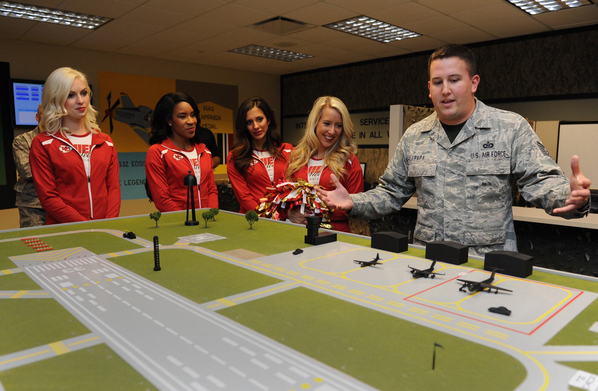 Tech. Sgt. Korey Papa, 334th Training Squadron instructor, shows an airfield model to Kansas City Chiefs cheerleaders during a tour at Cody Hall Sept. 30, 2016, on Keesler Air Force Base, Miss. The NFL cheerleaders visited Keesler to learn about the mission, hold a cheer clinic at the youth center and participate in a fashion show at the base exchange. (U.S. Air Force photo by Kemberly Groue/Released)