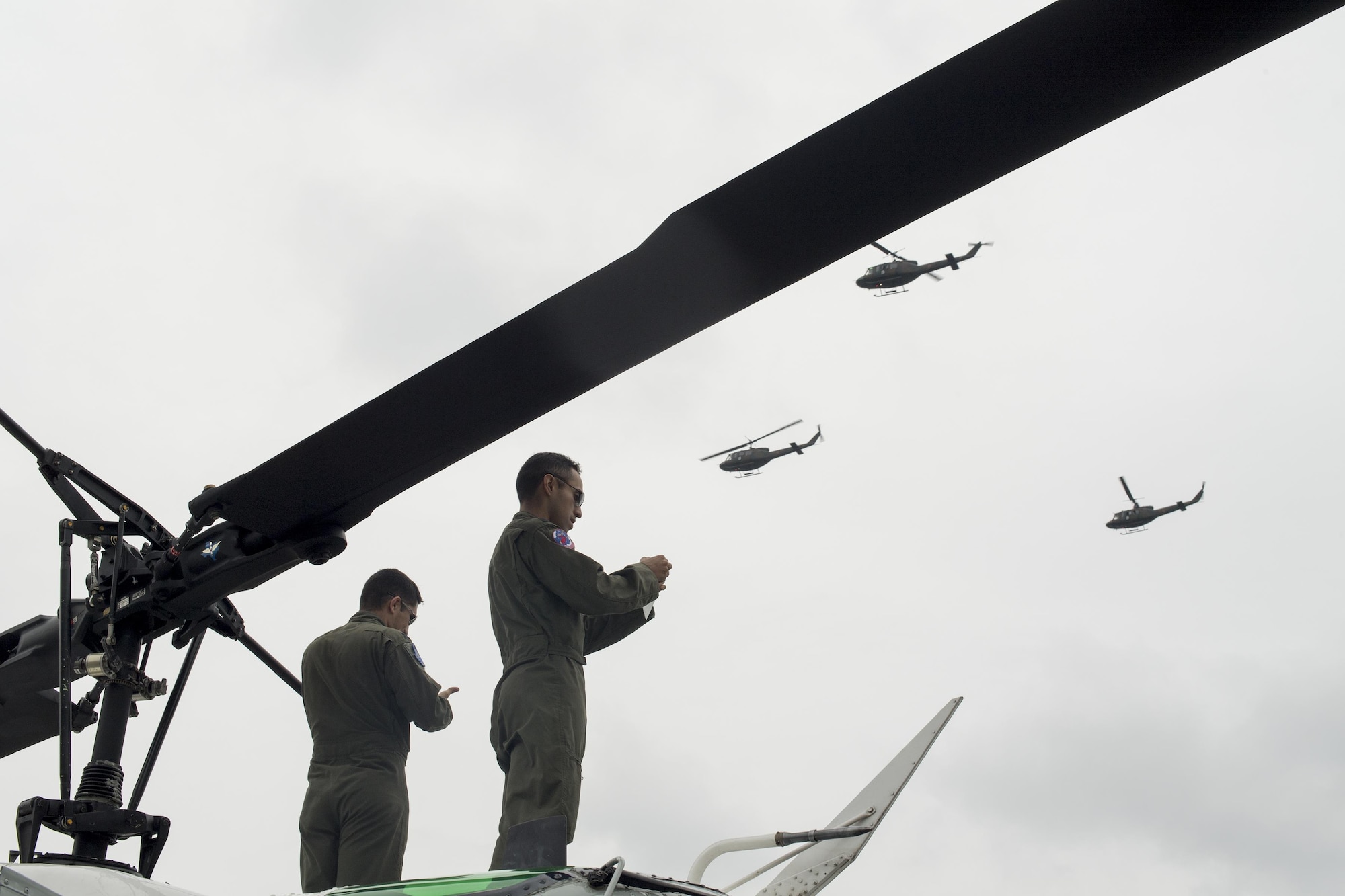 (Right to left) U.S. Air Force Capt. Jonathan Bonilla and Capt. Vicente Vasquez, 459th Airlift Squadron UH-1N Iroquois pilots, take photos of a Japan Ground Self-Defense Force UH-1J Huey formation flight display during the 43rd Anniversary Event of Japan Ground Self-Defense Force Camp Tachikawa at JGSDF Camp Tachikawa, Japan, Oct. 1, 2016.  JGSDF UH-1Js assigned to Eastern Army Helicopter demonstrated flight formations, hoist techniques and disaster relief procedures with first responders. Service members with the 459th Airlift Squadron from Yokota Air Base and Army Aviation Battalion from Camp Zama participated in the festival. (U.S. Air Force photo by Yasuo Osakabe/Released) 