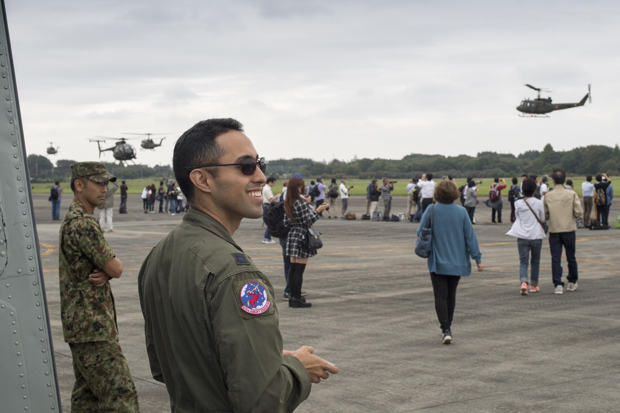 U.S. Air Force Capt. Jonathan Bonilla, 459th Airlift Squadron UH-1N pilot, watches a Japan Ground Self-Defense Force UH1-J formation flight demonstration during the 43rd Anniversary Event of Japan Ground Self-Defense Force Camp Tachikawa at JGSDF Camp Tachikawa, Japan, Oct. 1, 2016. JGSDF UH-1Js assigned to Eastern Army Helicopter demonstrated flight formations, hoist techniques and disaster relief procedures with first responders. Service members with the 459th Airlift Squadron from Yokota Air Base and Army Aviation Battalion from Camp Zama participated in the festival. (U.S. Air Force photo by Yasuo Osakabe/Released)